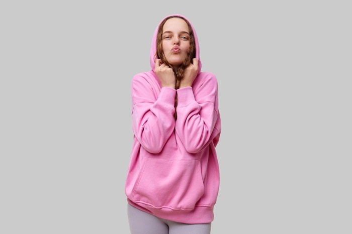 A,Young,Woman,Wearing,A,Bright,Pink,Hoodie,Playfully,Poses
